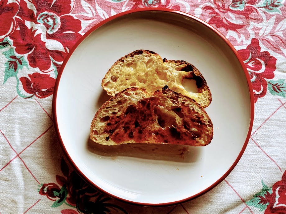 An image of sourdough toast with jam on a white plate.